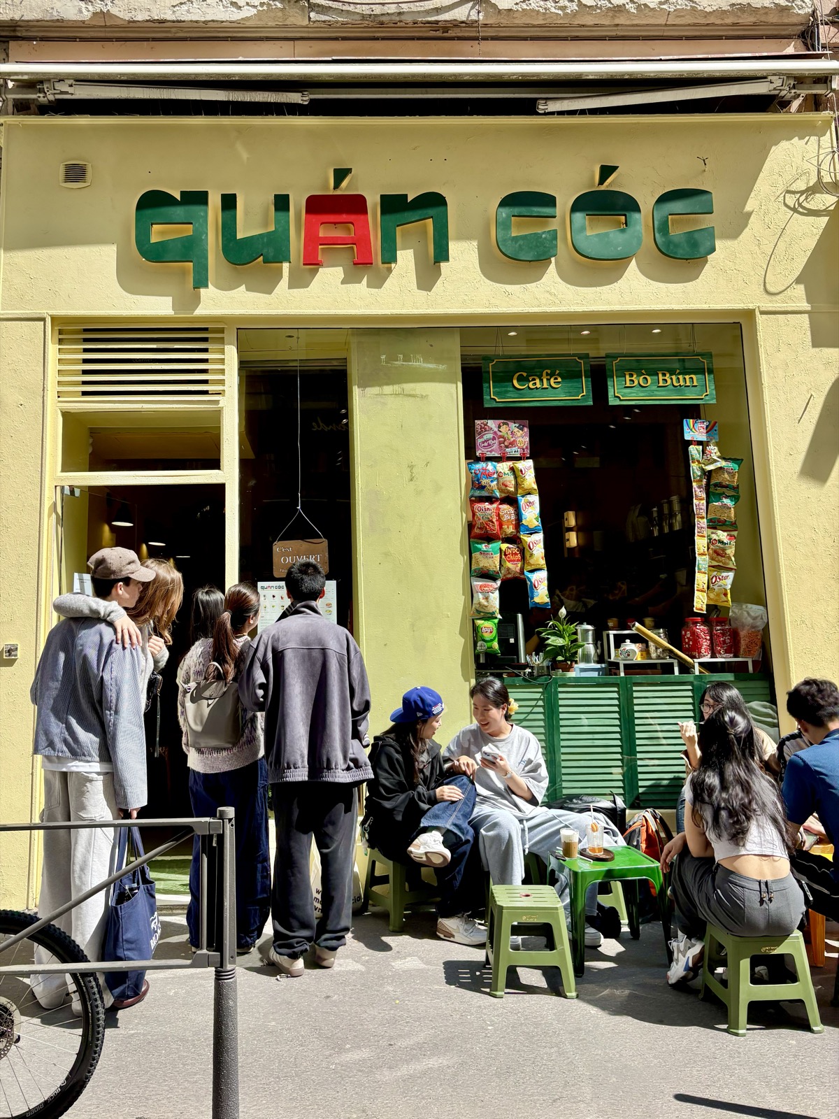 Des clients réunis sur les petits tabourets devant la façade jaune de Quán Cóc